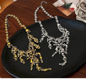 Macro shot of gold and silver skull necklaces with bone-shaped chains on a vintage plate
