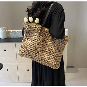 Detailed close-up of woven straw texture and premium brown leather straps on tote bag