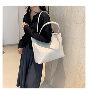 Detail showing off-white woven leather texture and rounded handles on a large tote bag