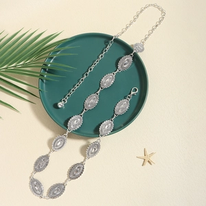 Detail of vintage silver waist chain with embossed oval metal pieces on a green plate