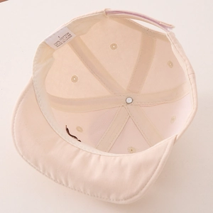 Internal detail of cream baby cotton cap showing 100% cotton label and velcro strap