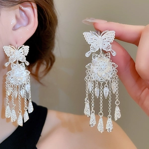 Detail of silver hollow butterfly earrings with flower charms and long chain tassels