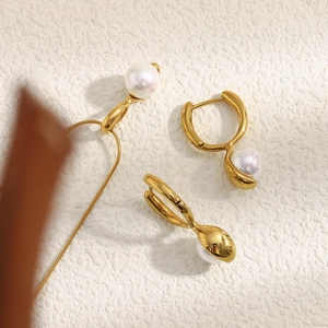 Detailed flat lay of 18K gold-plated necklace and pearl earrings set on texture background