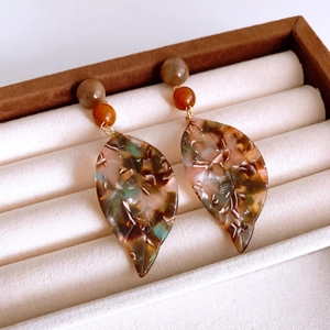 Detail of tortoise shell acetate leaf earrings with gold beads in a jewelry box