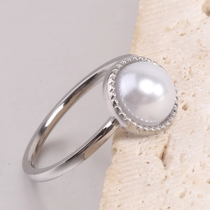 Macro detail of silver-tone steel ring featuring a large pearl and scalloped bezel setting