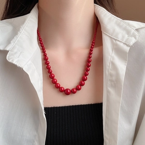 Gros plan d'un collier de perles rouges dégradées avec finition polie sur un mannequin
