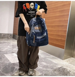 Detail of vintage denim backpack showing patchwork design and front zipper pocket