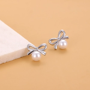 Détail macro de boucles d'oreilles nœud argentées avec élégantes perles blanches