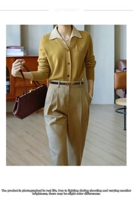 Detail of a thin black leather belt with a golden M-shaped buckle on casual trousers