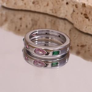 Macro detail of silver ring with pink teardrop and green rectangle cubic zirconia