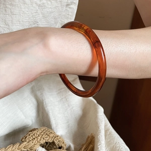Detail of amber resin round bangle on a model's wrist with a warm natural vibe