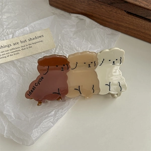 Detail shot of cute puppy hair claw clip with Ideal Cycle text on creamy resin
