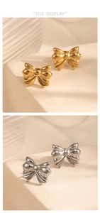 Detail showing polished gold and silver bow stud earrings on a white stone base