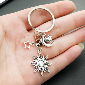 Minimalist sun moon star heart alloy keychain charms for bags and keys held in hand