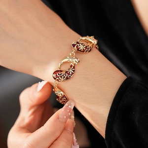 Detail of vintage gold bracelet with red enamel flowers and sparkling crystals on wrist
