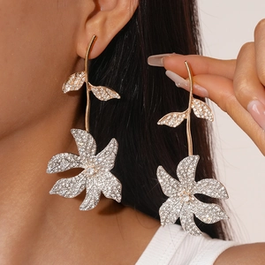 Detailed view of long flower drop earrings featuring sparkling rhinestones on golden stems