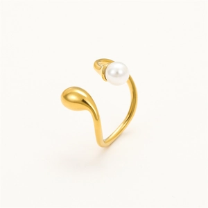 Macro shot of gold teardrop design and white pearl on a stainless steel open ring