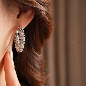 Macro view of silver hoop earring with paved sparkling crystals worn by model