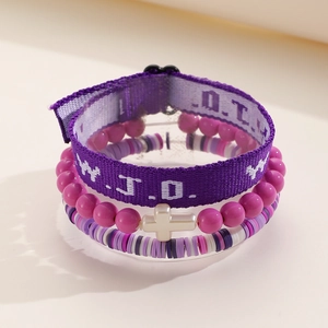 Close-up of WWJD embroidered purple fabric strap with cross pendant and beaded bracelets