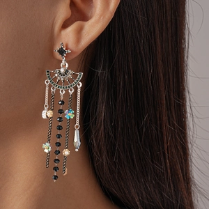 Détail de boucles d'oreilles à pompons argentés avec perles noires et fleurs sur modèle