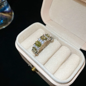 Close-up of vintage oval olive green gemstone ring with diamonds in a velvet box