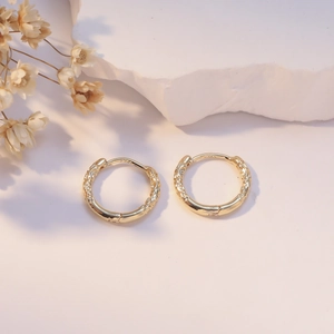 Vintage gold hoop earrings with embossed texture and S925 silver posts on a stone background