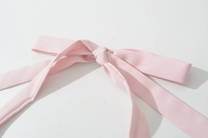 Détail d'un nœud en tissu rose à la taille sur une robe longue fendue élégante
