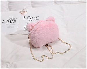 Detail of pink faux fur crossbody bag featuring animal ears and a golden metal chain strap