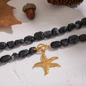 Irregular black resin necklace with a large gold starfish pendant and toggle clasp