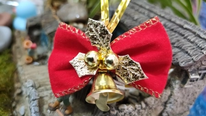 Close-up of a red velvet Christmas bow with golden bells and holly leaves decorations