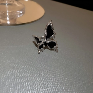 Macro detail of silver liquid metal butterfly ring with black enamel inlay and polished finish