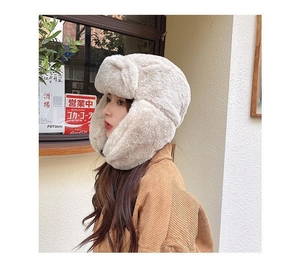 Detail of warm faux fur earflap hat in beige, showing soft plush texture for winter
