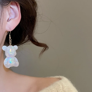 Close-up of model wearing transparent rainbow resin bear earrings with gold hooks