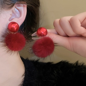 Detail showing a model wearing red plush faux fur pom pom earrings for autumn and winter