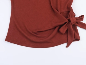 Détail du haut en maille côtelée rouge rouille avec nœud latéral et texture douce
