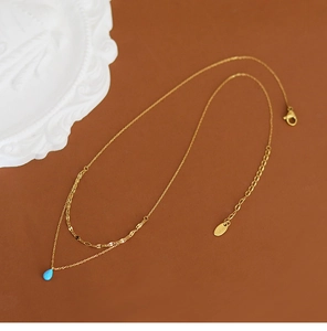 Detail of 18K gold-plated double-layer necklace with a blue teardrop faux opal pendant