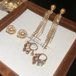 Three-piece gold-tone earring set featuring round pearls, tassels, and sparkling rhinestones