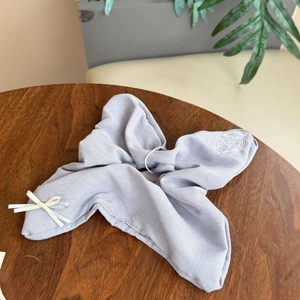 Detail of light purple linen bow hair clip with white floral embroidery and ribbon accent
