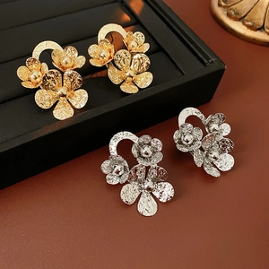 Detailed macro view of textured gold and silver floral stud earrings on jewelry box