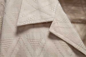 Macro view of beige jacquard weave shirt featuring textured geometric patterns and lapel