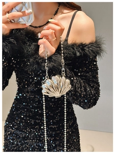 Silver shell-shaped metal mini bag with chain strap shown on a model for scale