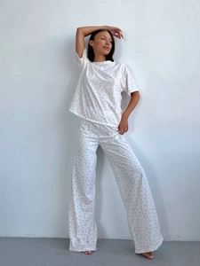 Detail shot of women's floral pajama set with pink heart patterns on a white background
