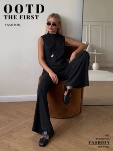 Detail of elegant black sleeveless turtleneck top and wide-leg trousers set with silk texture