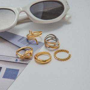 Detailaufnahme eines 5-teiligen Schlangenring-Sets in Gold und Silber auf einem Magazin