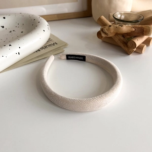 Detailed shot of beige handmade sponge headband with woven fabric texture and label