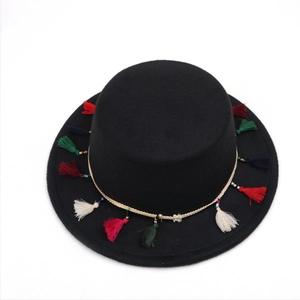 Détail d'un chapeau en feutre noir avec des glands colorés et un ruban tissé ethnique