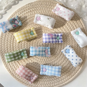 Cute colorful fabric cable organizers with heart buttons on a woven mat display