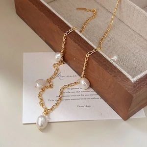 Close-up of irregular baroque pearl necklace on gold Figaro chain and wooden jewelry box