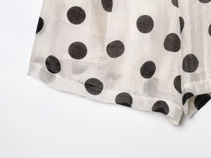 Close-up of black and white polka dot fabric texture with hemmed edge detail