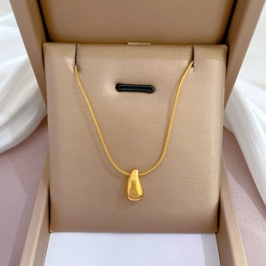 Close-up of golden teardrop pendant necklace in a luxury gift box with silk fabric